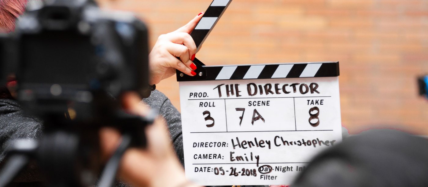 A clapperboard held up in front of a camera on set just before a take