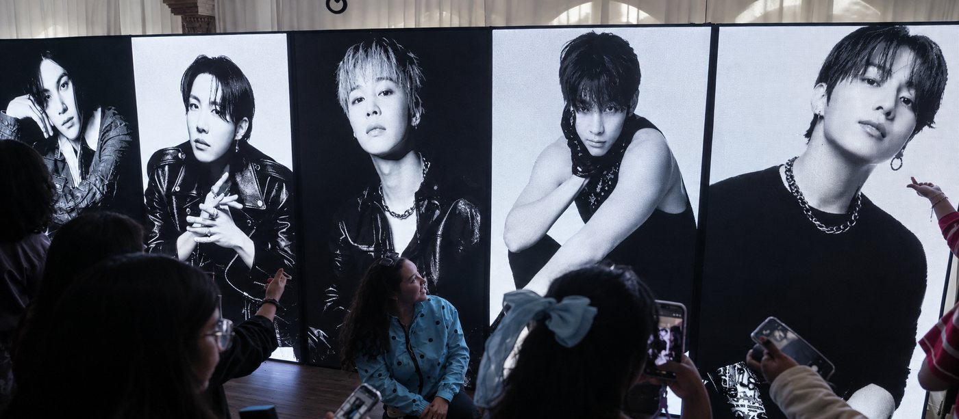 BTS Latin America tour 2026: fans take photos in front of black-and-white portrait screens of the members
