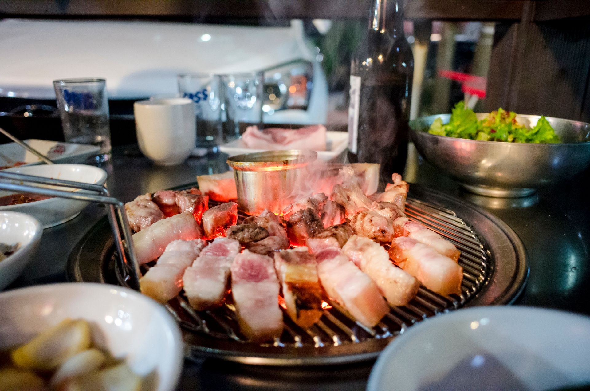 Korean BBQ at home — samgyeopsal pork belly on a tabletop grill with ssam lettuce and ssamjang