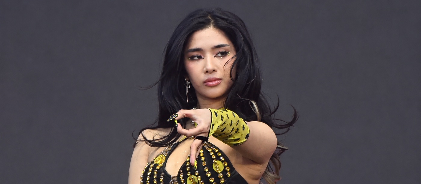 Sophia’s return to KATSEYE article cover, showing the singer performing in a black and yellow stage outfit